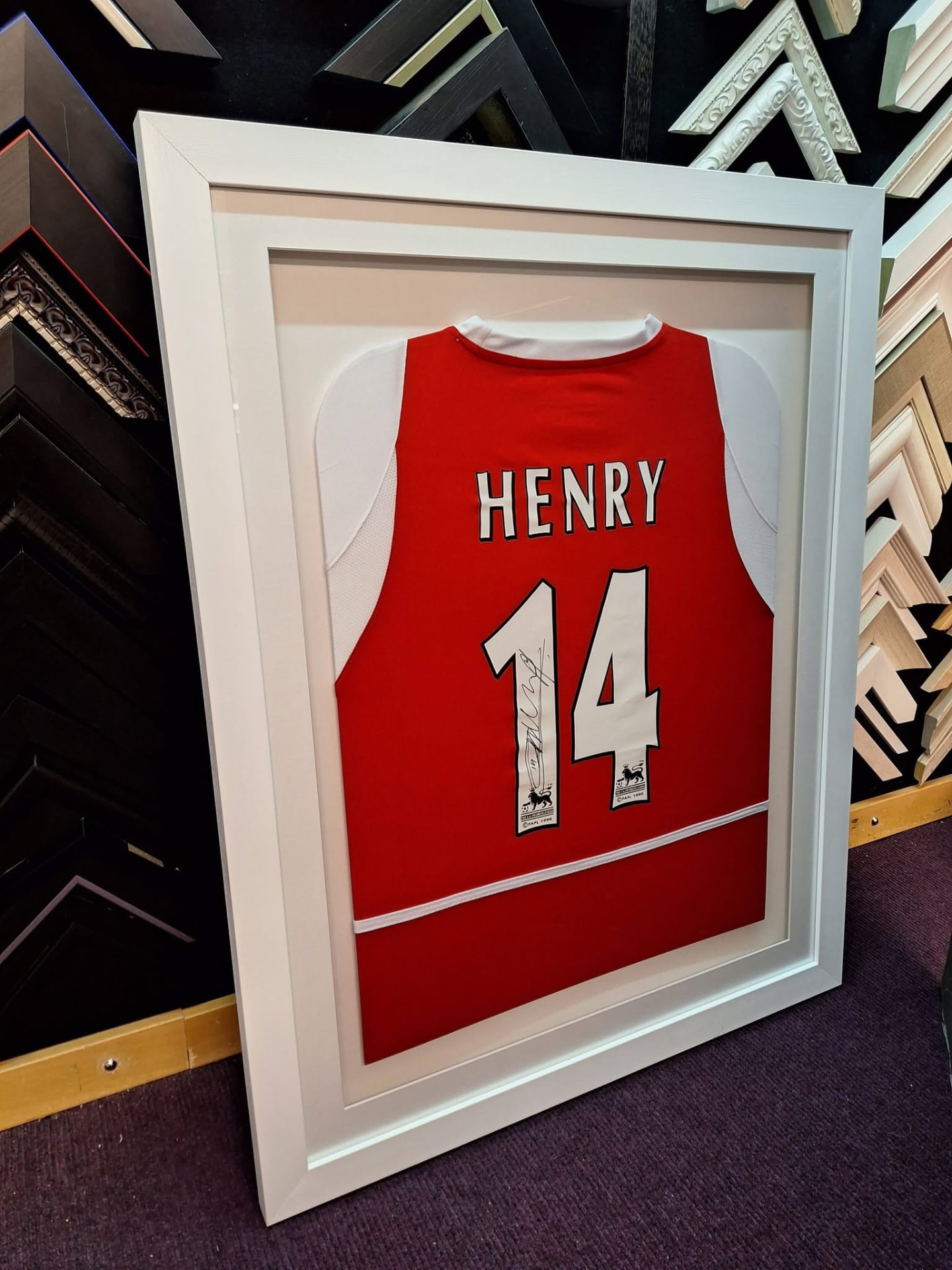Framed football shirt above a walnut console table