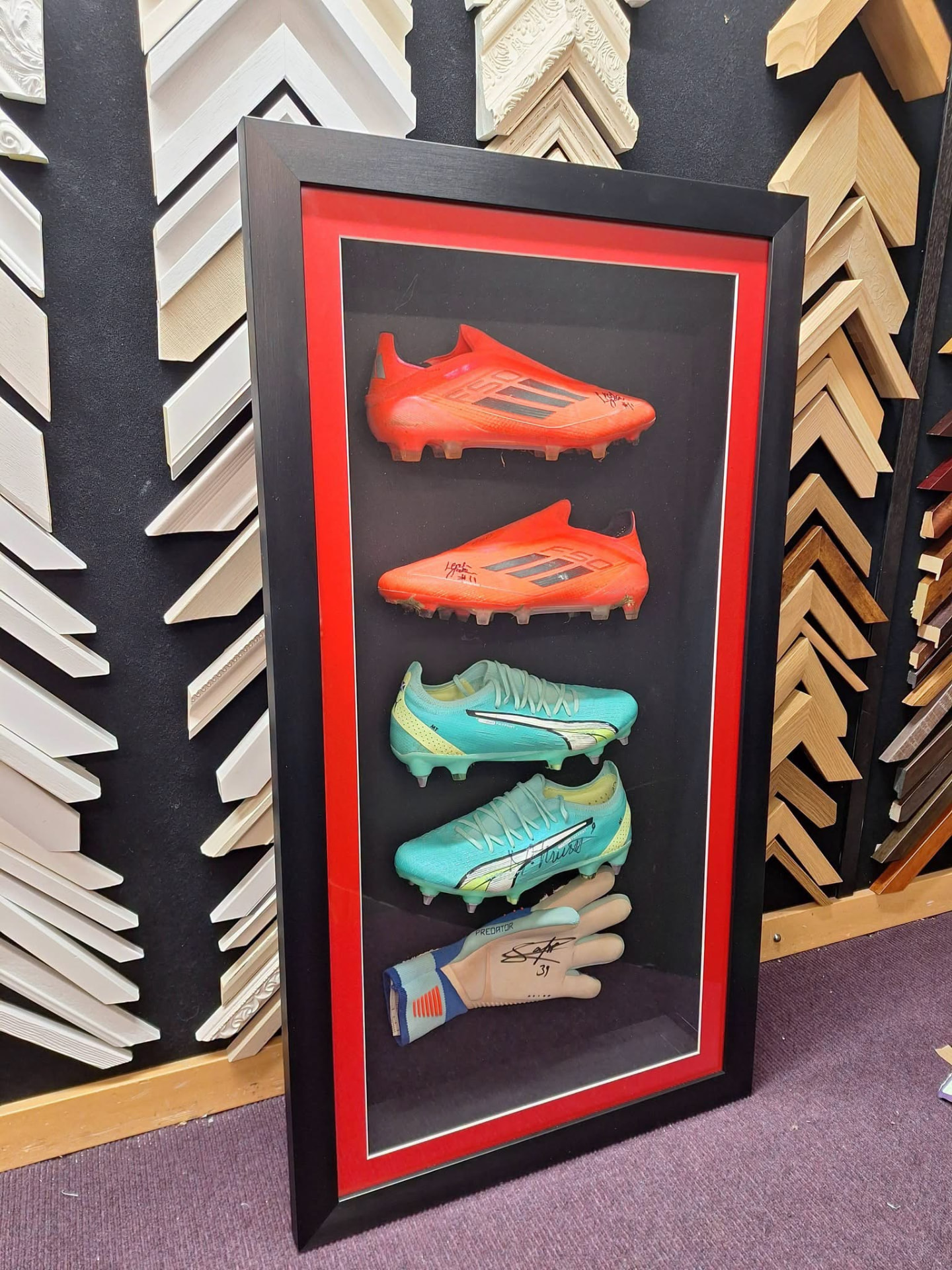 Signed football boots and goalkeeper glove in a deep display frame with red mount