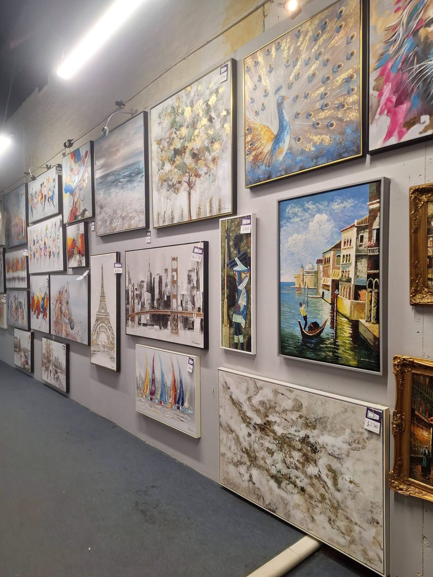 A gallery wall of framed artwork, from paintings to a Venetian canal scene