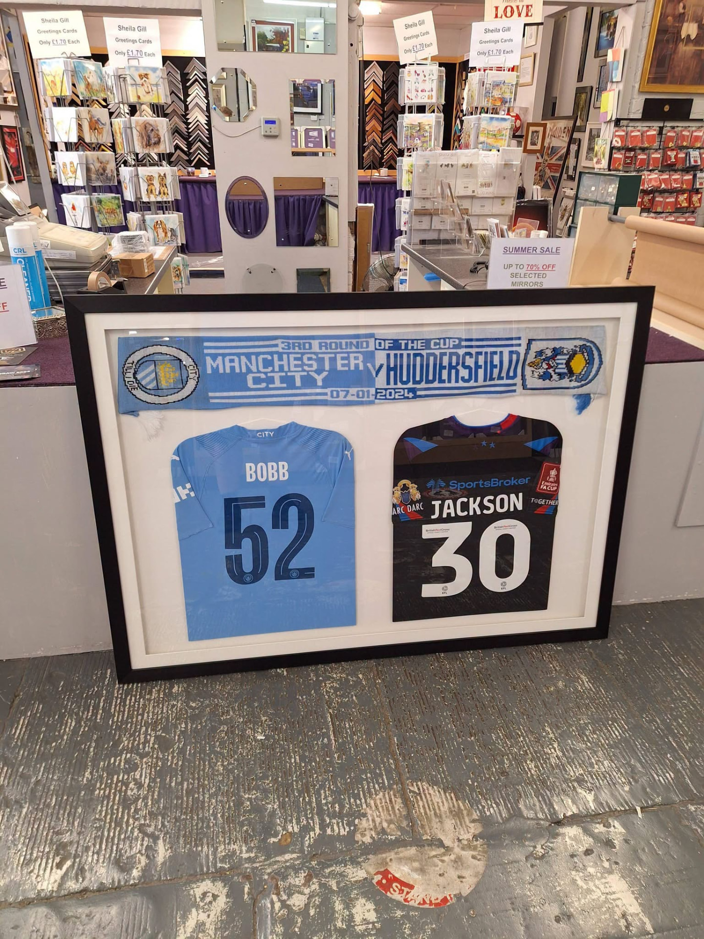 Two shirts and a cup-tie scarf framed in one display
