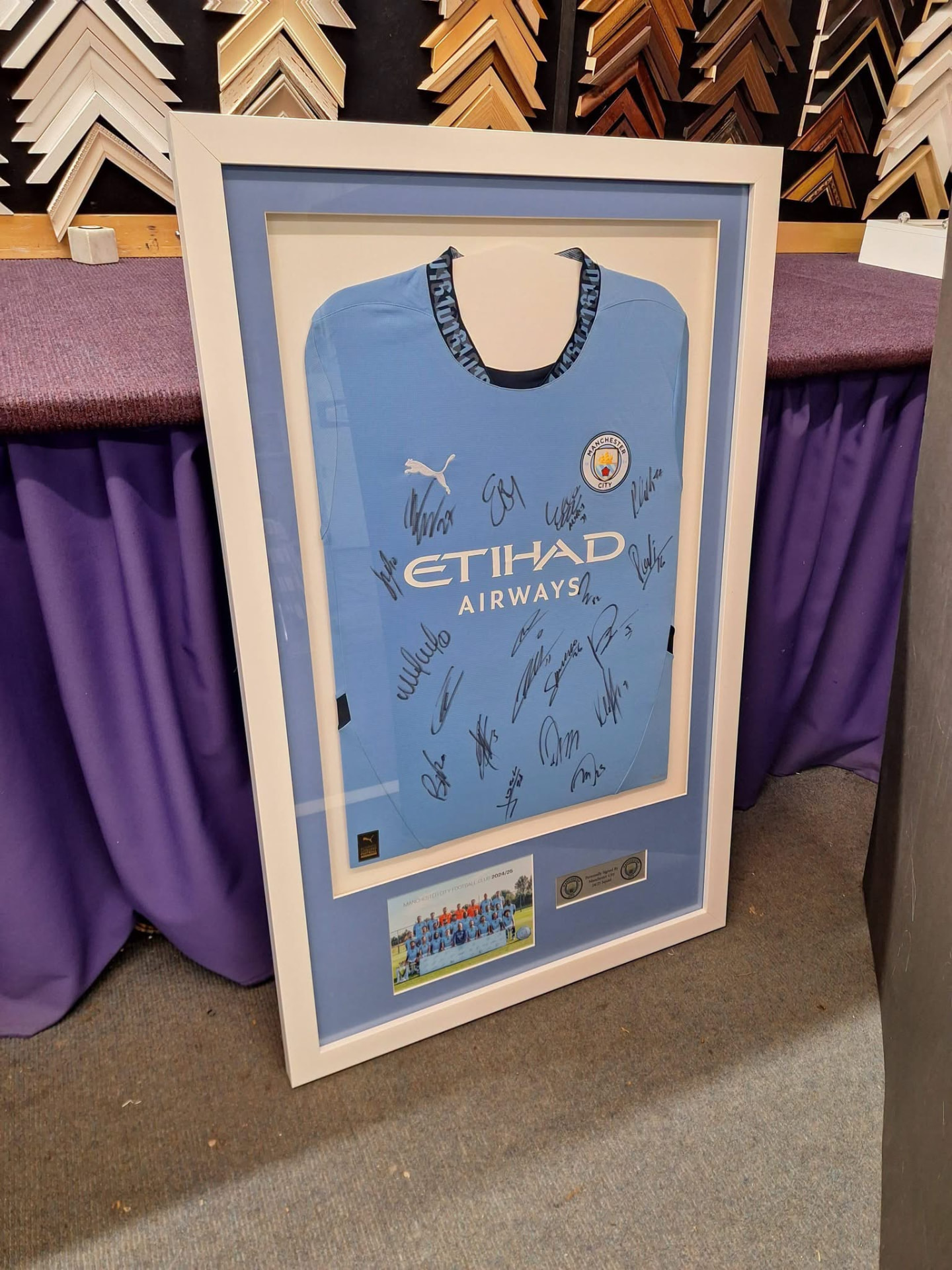 Signed Manchester City shirt in a cream-and-blue mount with a team photograph